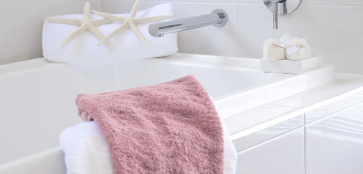 A pink towel is on the edge of a white sink.